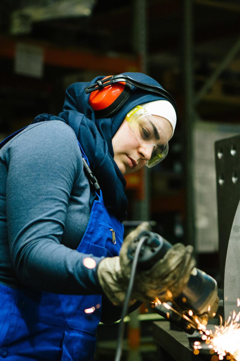 Huivipäivinen hitsaaja hitsaa metallilevyjä kuulosuojaimet päässä.