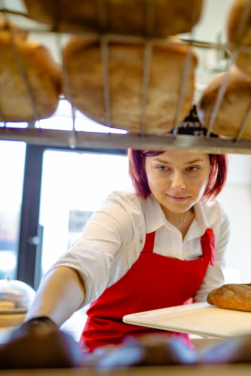 Leipomotyöntekijä asettelee patonkeja hyllylle.